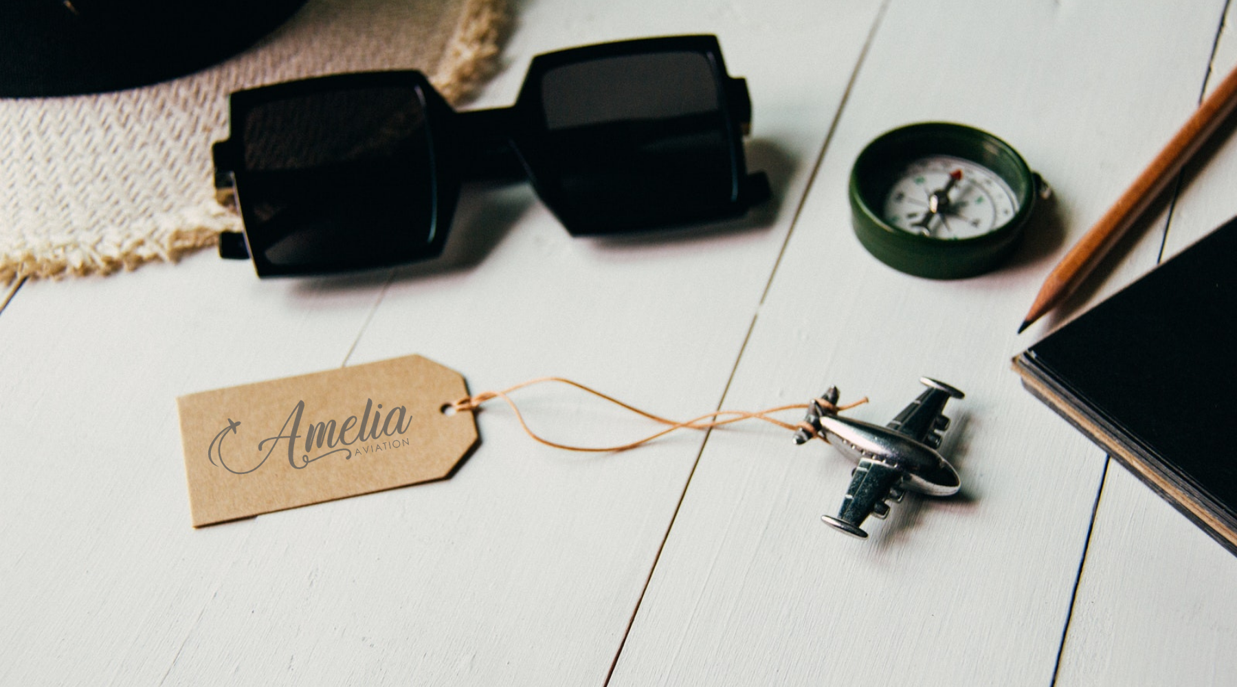 image with aviation memorabilia like small airplane, compass, sunglasses, pencil and notebook